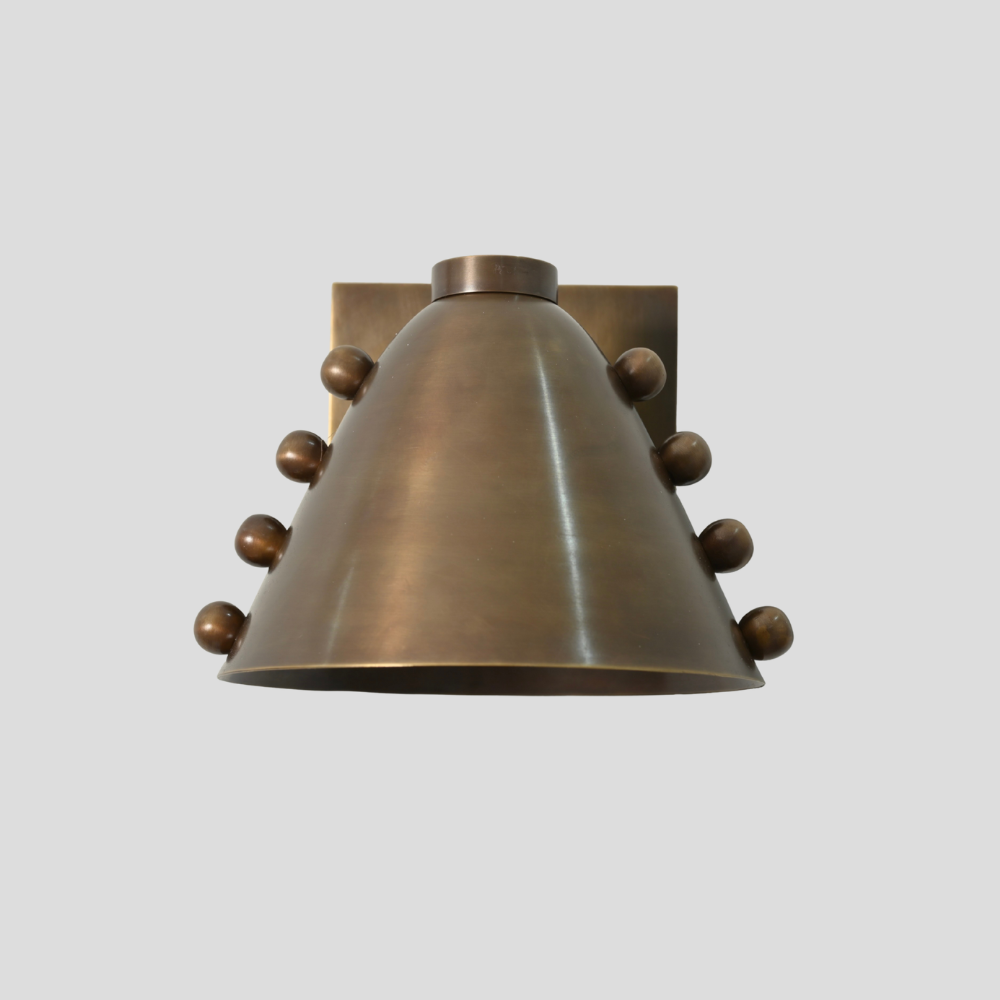Bronze wall sconce with decorative elements on a light gray background
