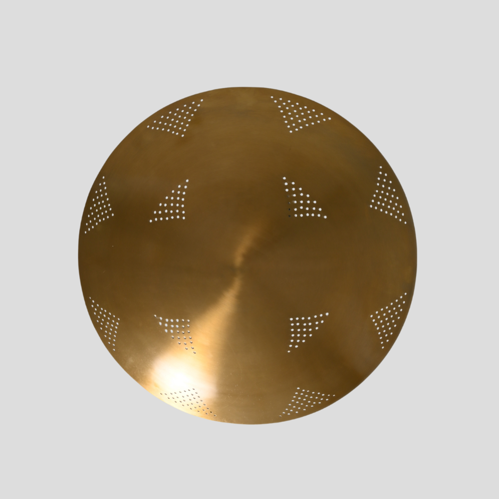 Round brass disc with geometric perforations on a light gray background