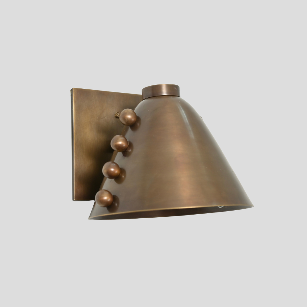 Bronze wall sconce with decorative elements on a light gray background