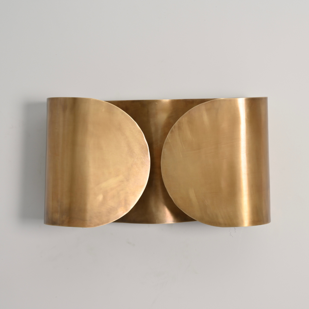 Mid century butterfly wall sconce handcrafted with a pure raw brass finish on a gray wall