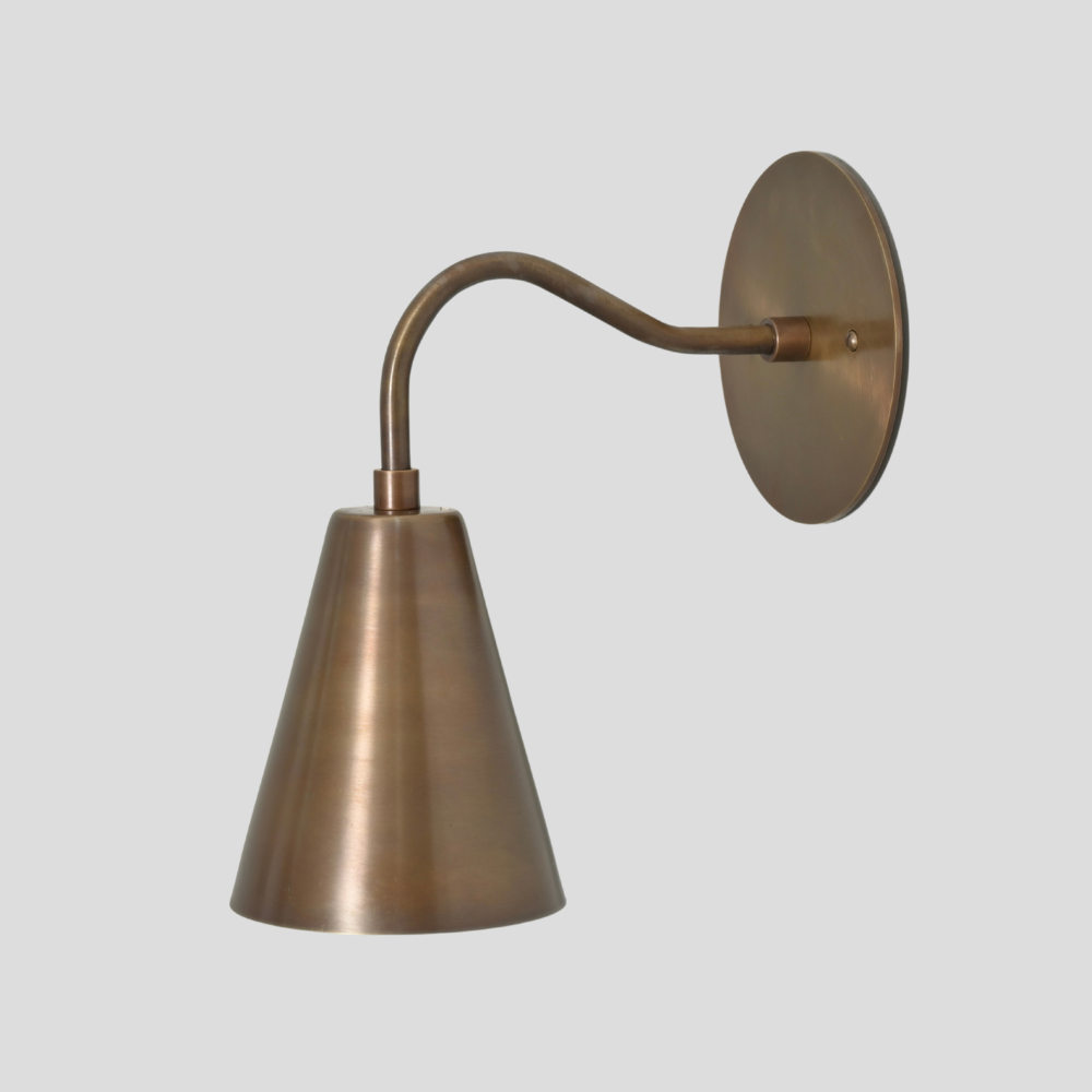 Mid Century modern brass wall sconce with curved arm on a light gray background