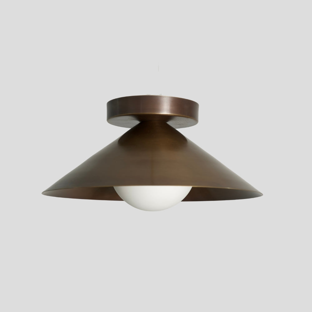 A mid century brass cone shade flush mount on a gray background