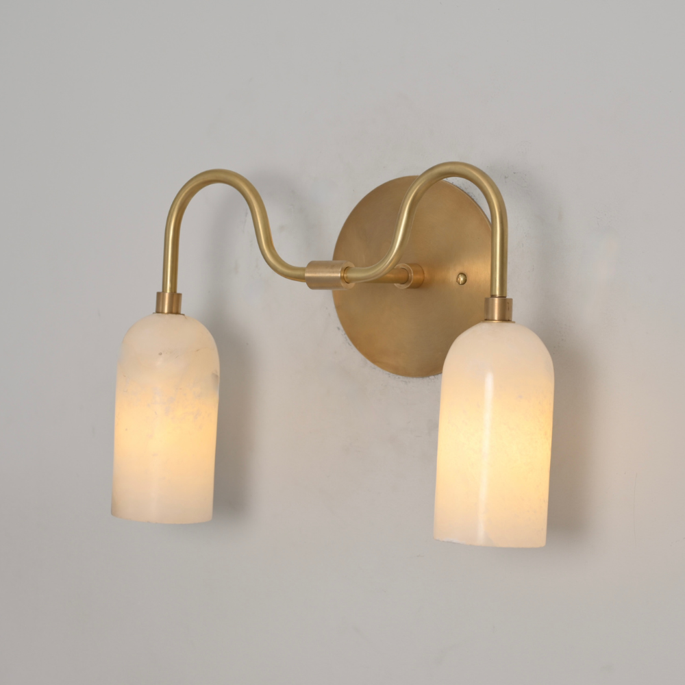 Luxury brass wall sconce with curved arm and glowing alabaster tubes
