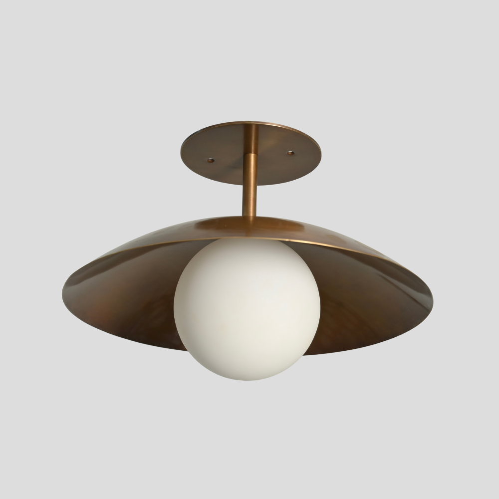 Ceiling light fixture with antique brass finish and white glass shade on a gray background