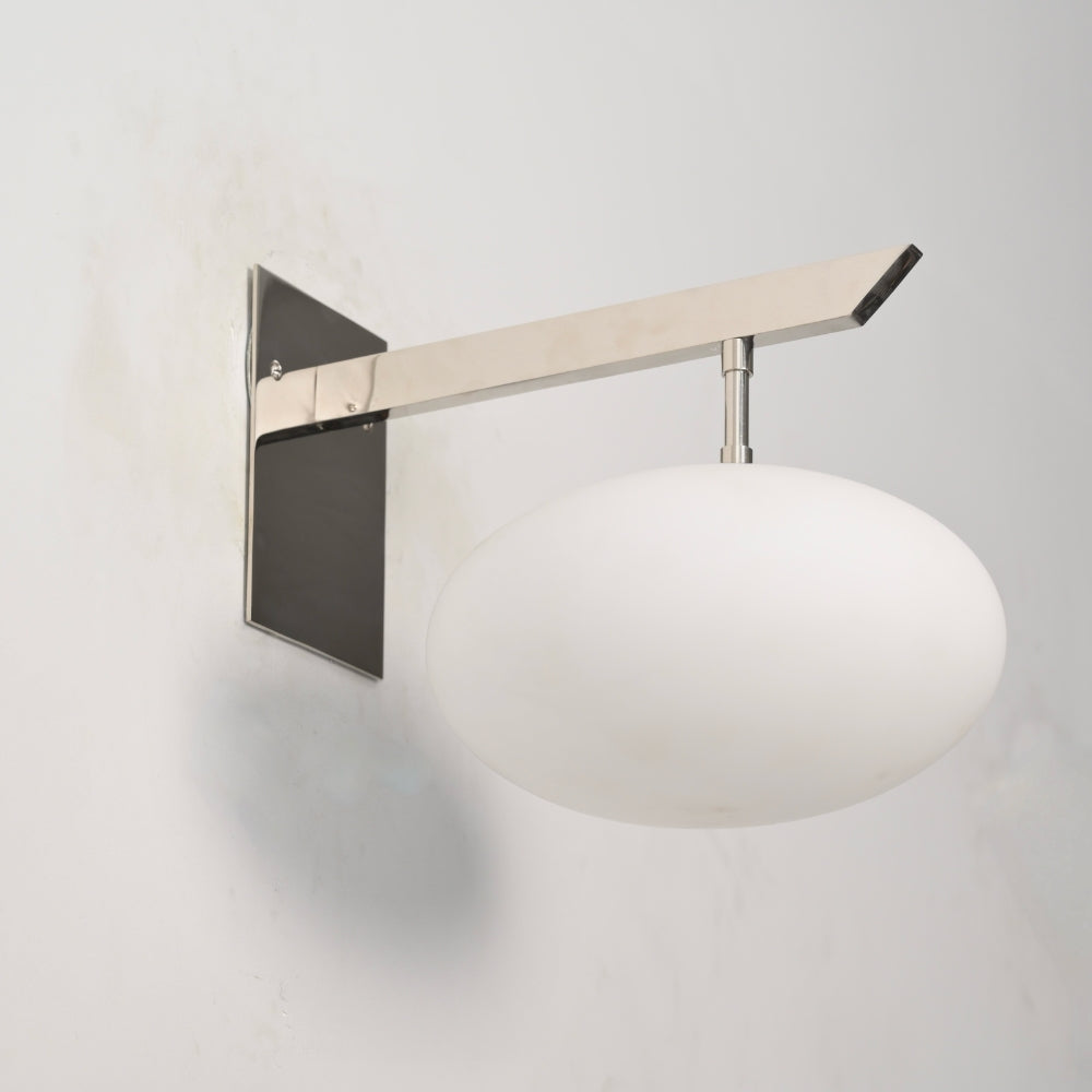 Brass wall lamp with a milky glass globe on a gray background