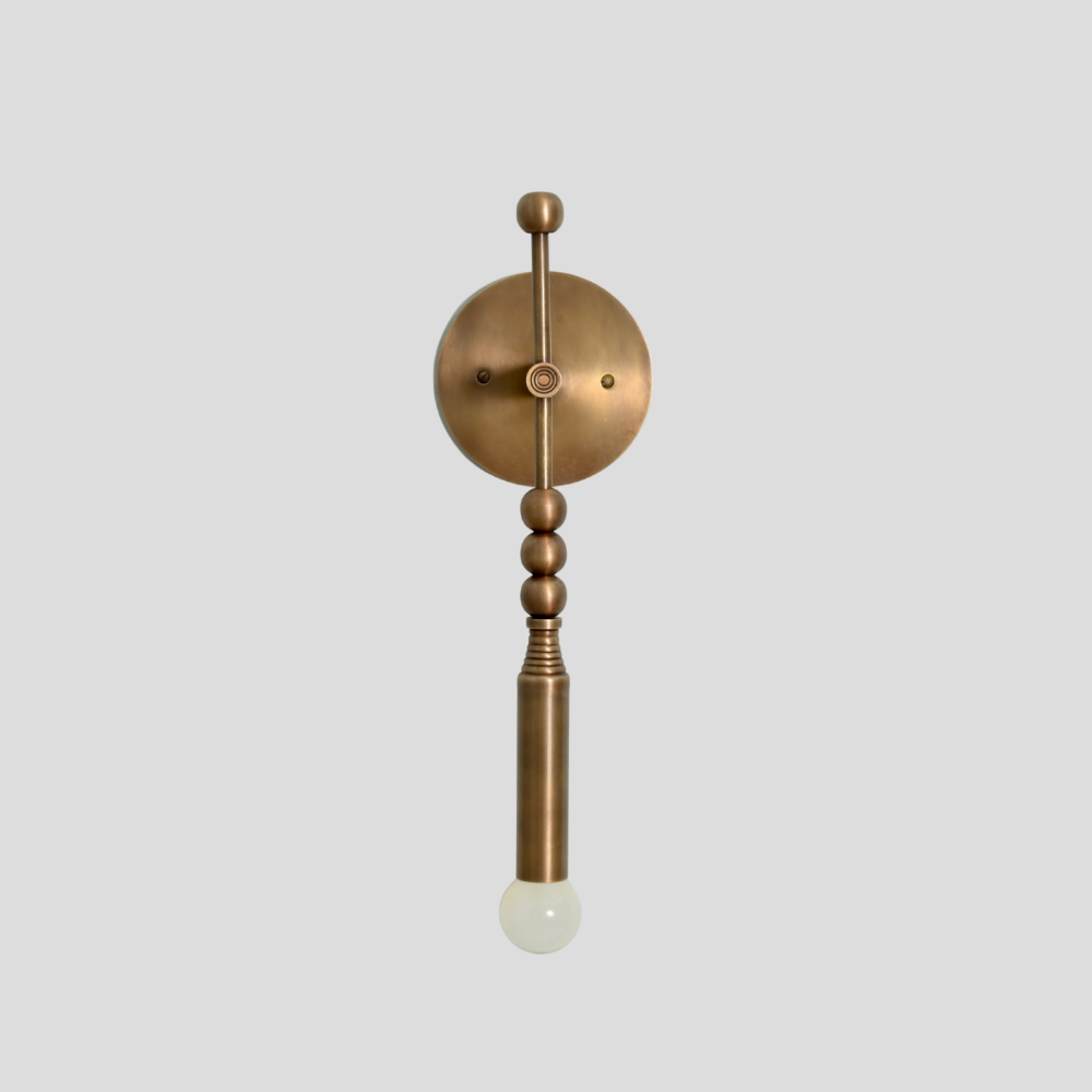 Antique brass wall sconce with a vertical arm and a minimalist glass globe designed by LightCove