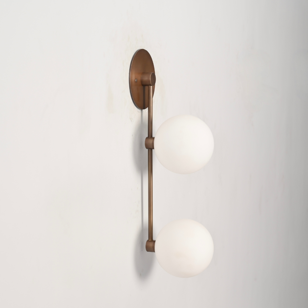 Double brass globe wall sconce with a vertical rod on a gray wall by LightCove