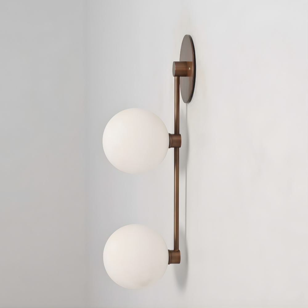 Modern wall sconce with two round glass shades on a plain background
