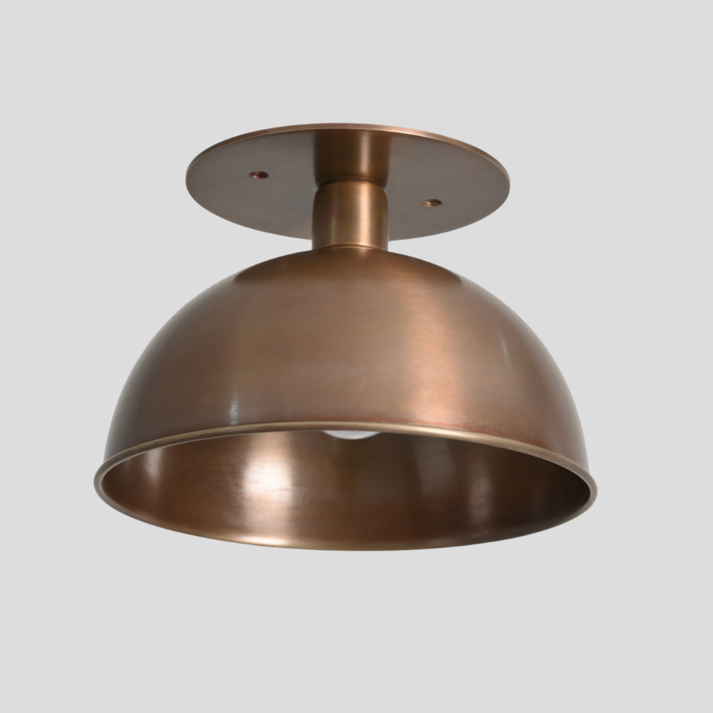 Semi flush mount with bowl design brass shade on a gray background.