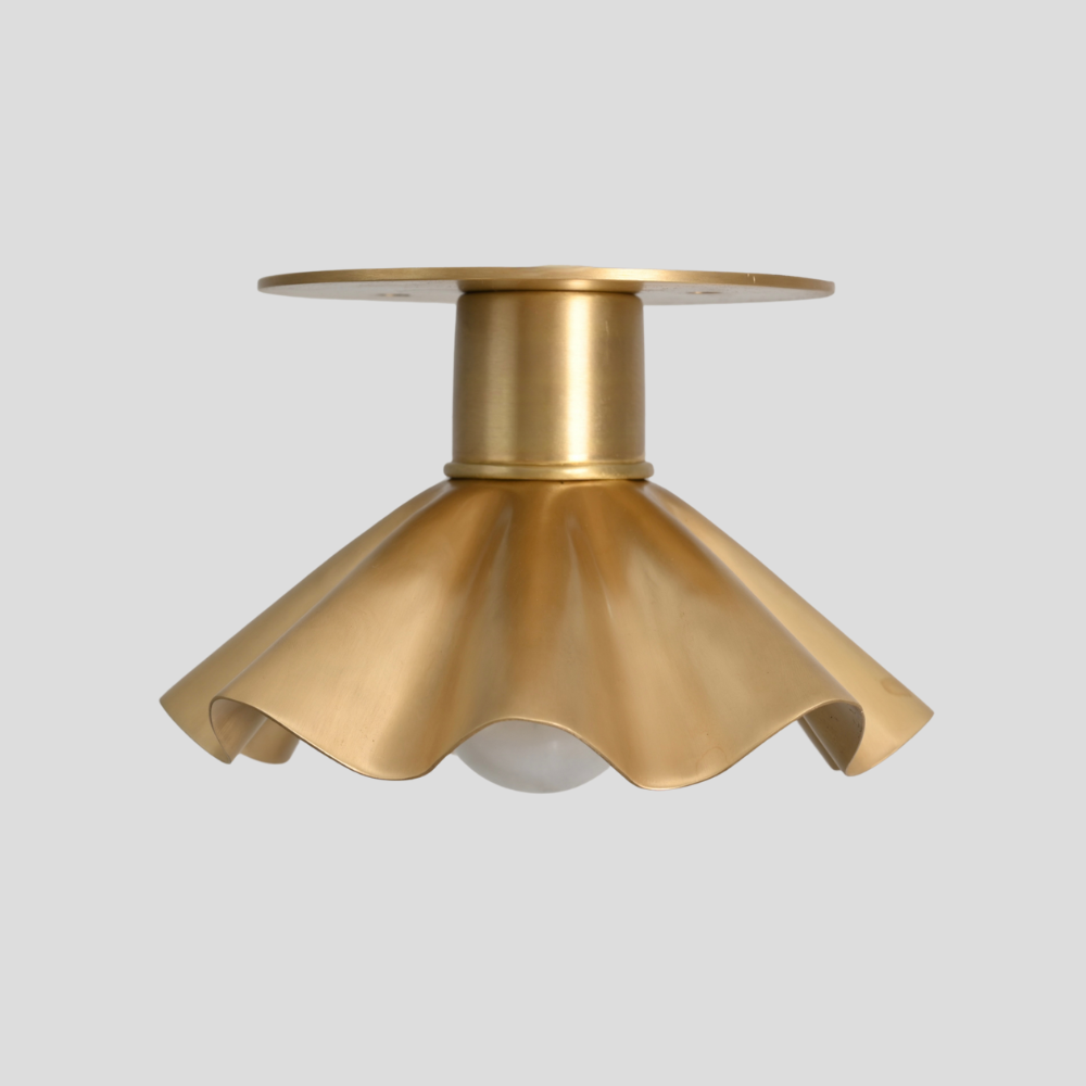 Mini flush mount with a raw brass finish and a petal shade design by LightCove on a gray background