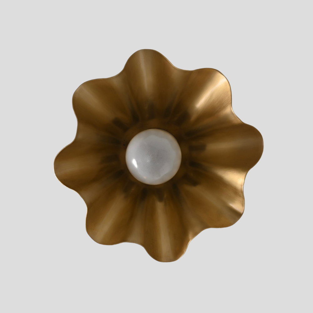 Decorative petal raw brass light fixture on a gray background