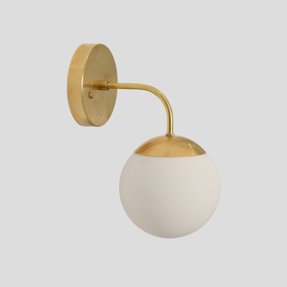 Vintage modern wall sconce with a frosted glass globe and a pure raw brass finish