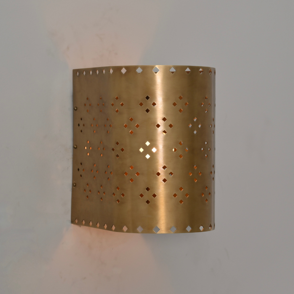 Perforated brass wall sconce with warm ambient light