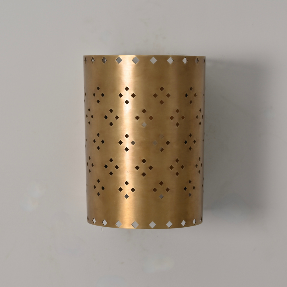 Mid century brass wall sconce casting decorative light patterns