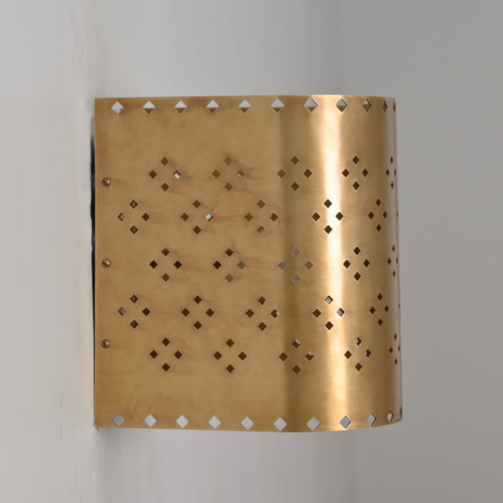 Decorative brass wall sconce with diamond cut perforations