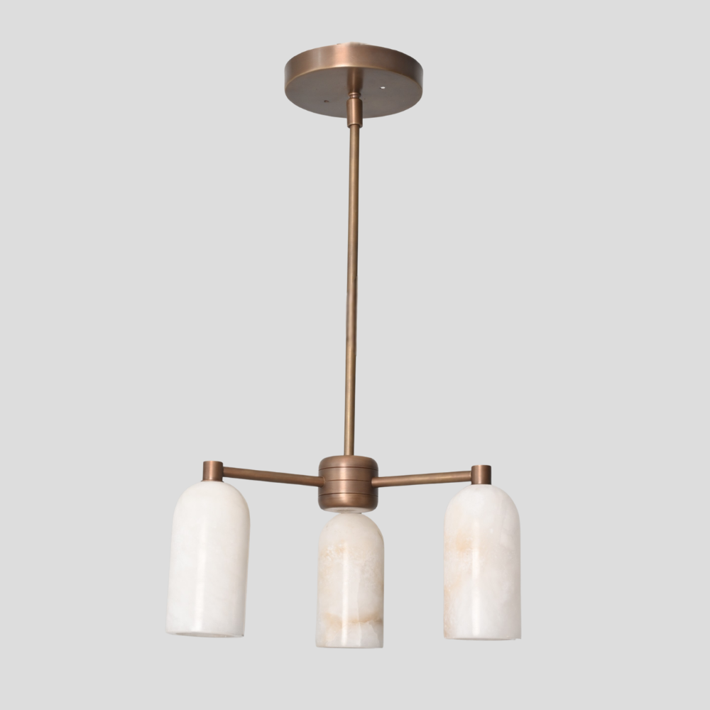 Modern pendant light with three white marble shades and brass metal fixture on a gray background