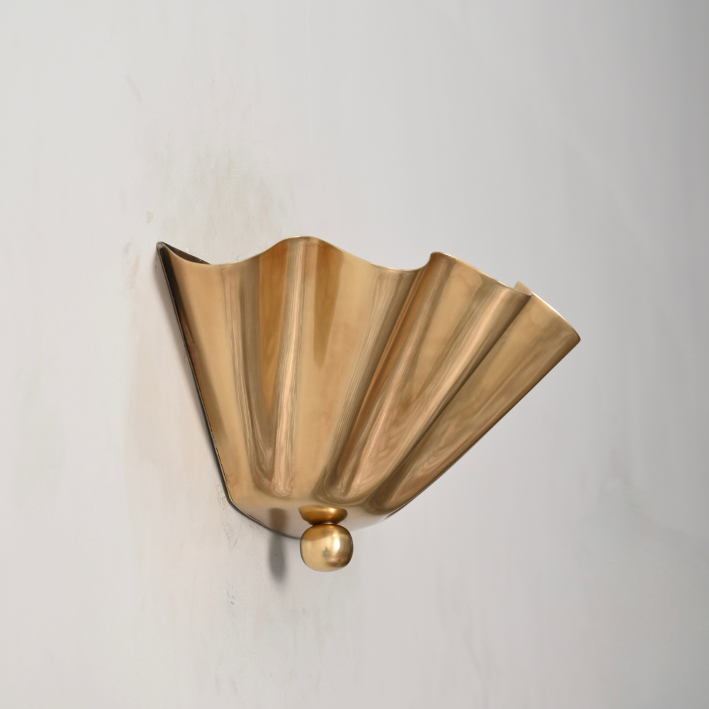 Close up on the raw brass finish of this flower shaped shade wall lamp