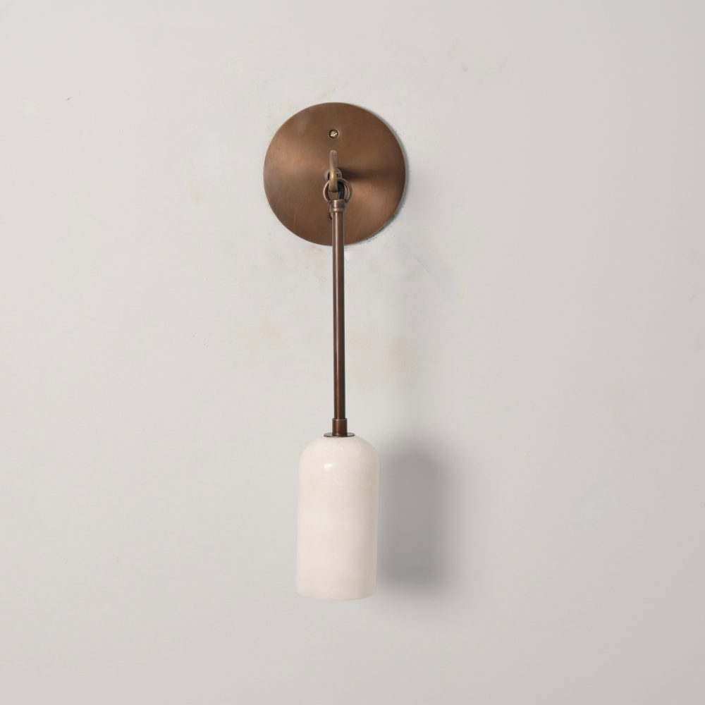 modern brass pendant arm with cylinder alabaster shade on a gray wall