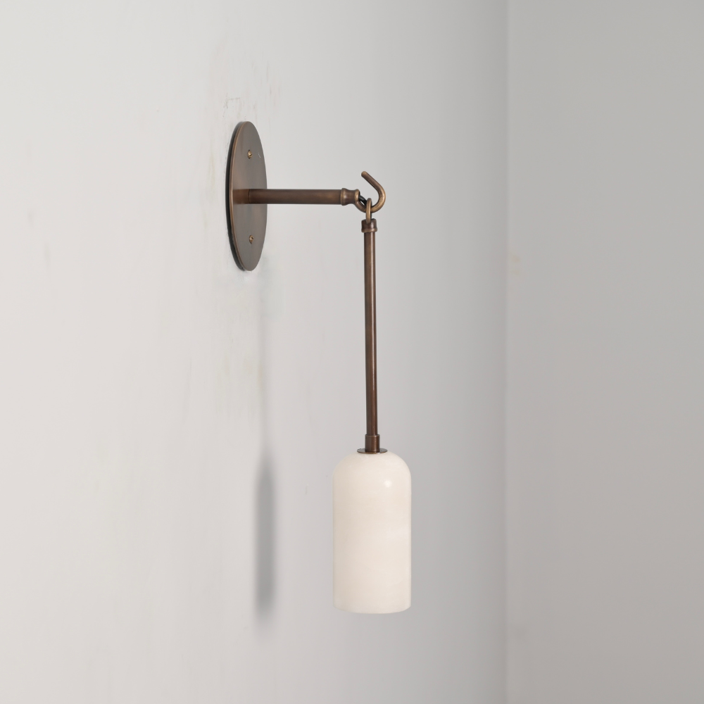 Marble shade wall sconce in a mid century modern design on a gray wall