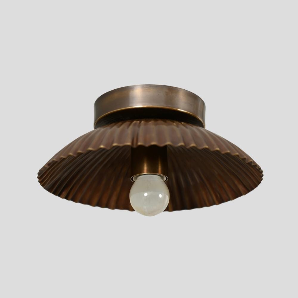 A brass finish ceiling light fixture with a pleated shade, showcasing a single bulb.