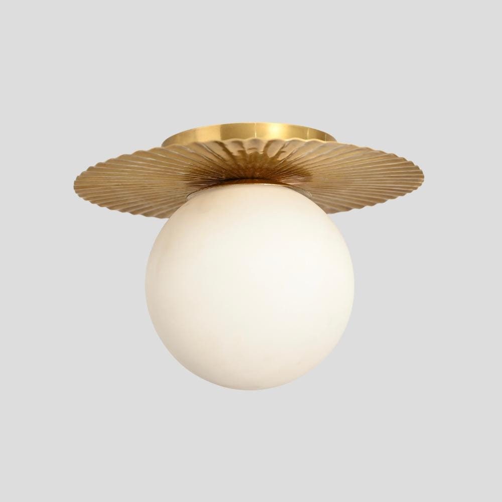 A flush mount ceiling light with a brass base and a milky white glass globe.