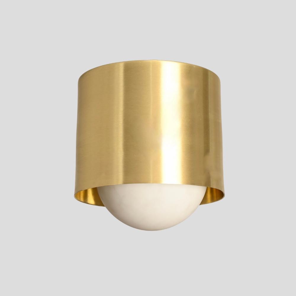 A modern wall flush mount light with a minimalistic brass finish and a handmade glass globe.