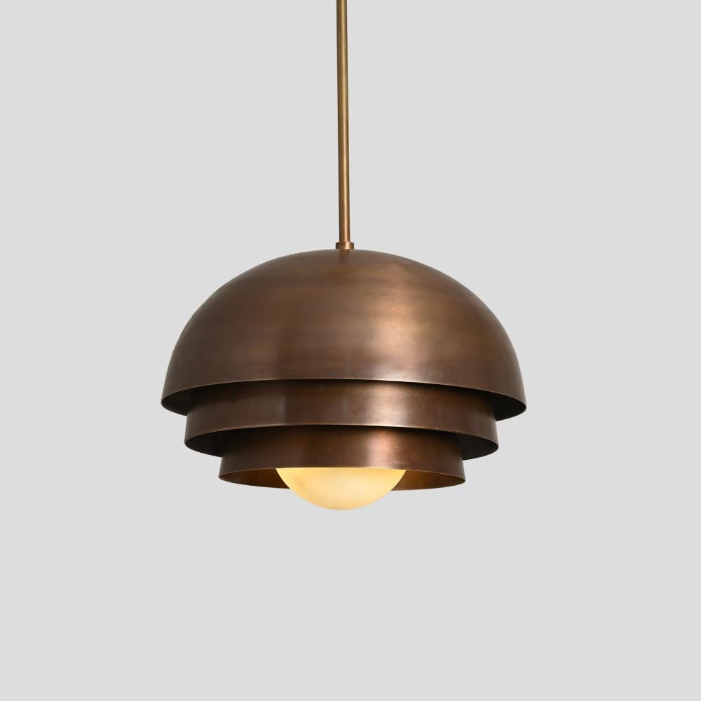 A bronze pendant lamp shade with a glass globe and antique brass finish hanging from a ceiling fixture.