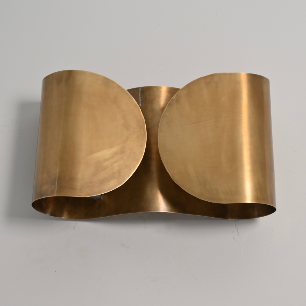 Modern double brass curved shade wall sconce on gray wall 