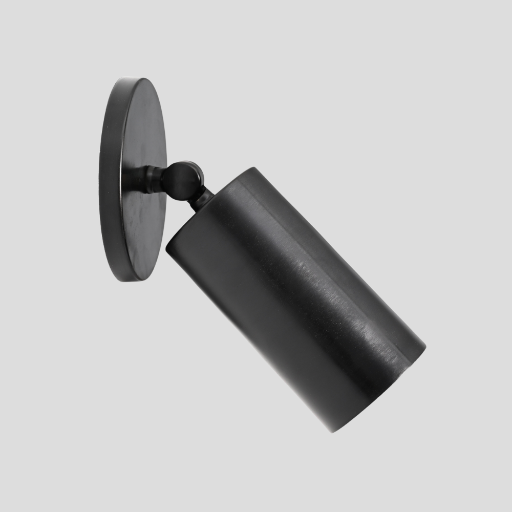 Mid century anitque black brass adjustable sconce on a gray background. 