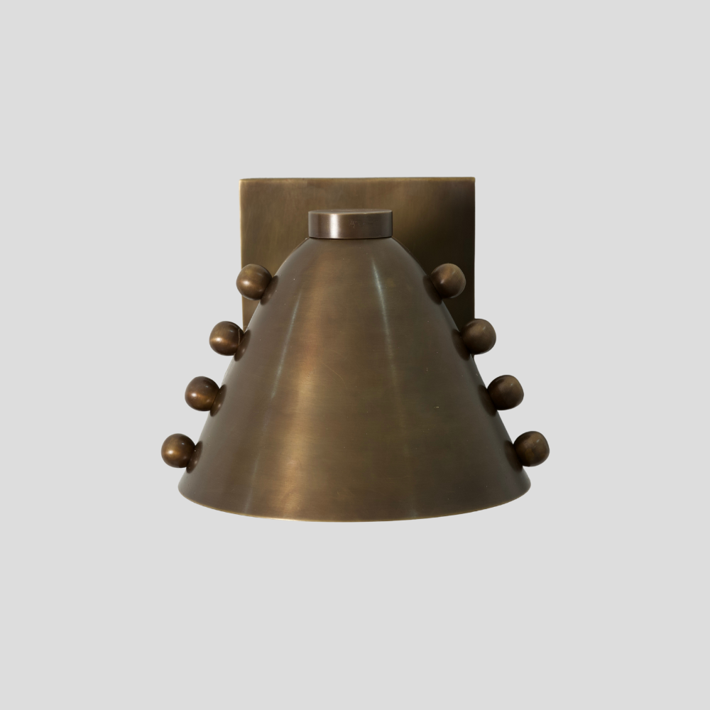 Brass wall sconce with decorative elements on a light gray background