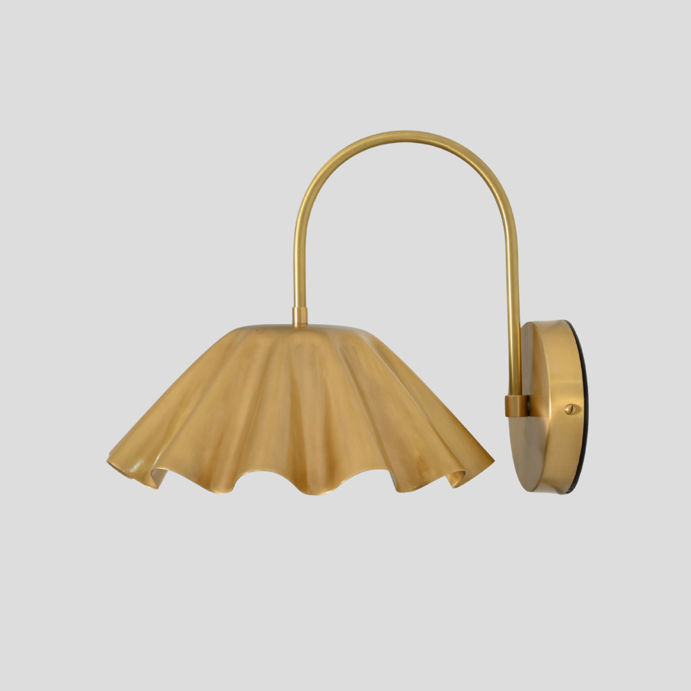 Gold wall-mounted lamp with a scalloped shade on a light gray background