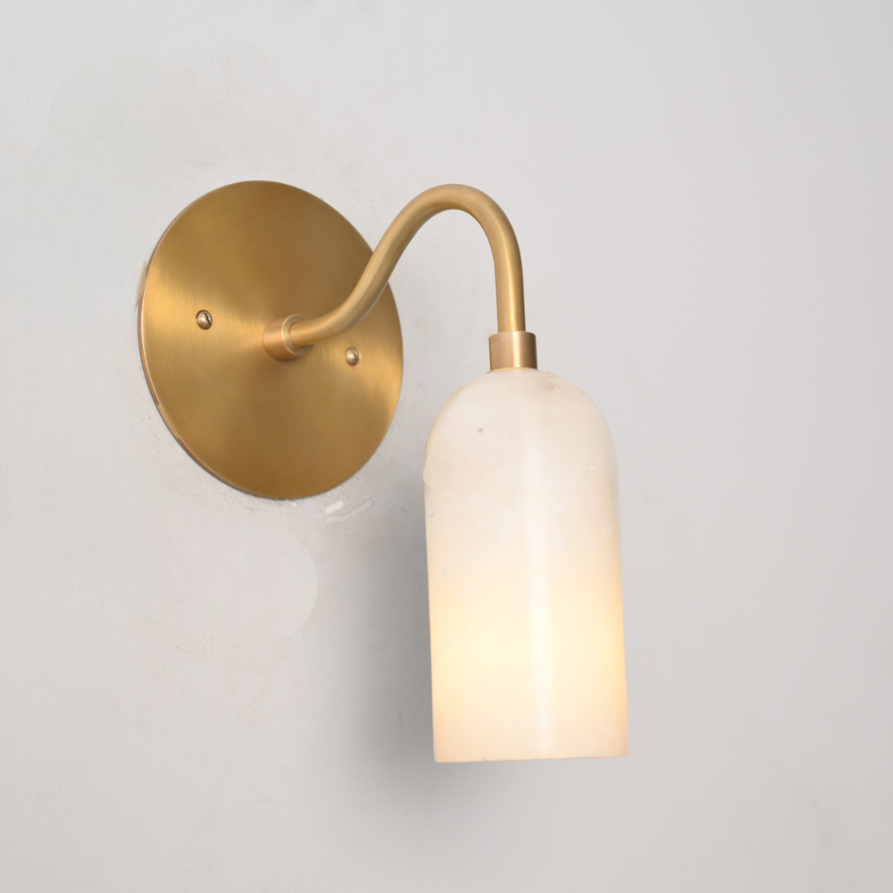 Curved brass arm wall sconce with cylindrical alabaster shade