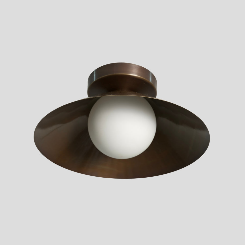 close up on the opal glass globe from a handcrafted cone shade flush mount in antique brass 