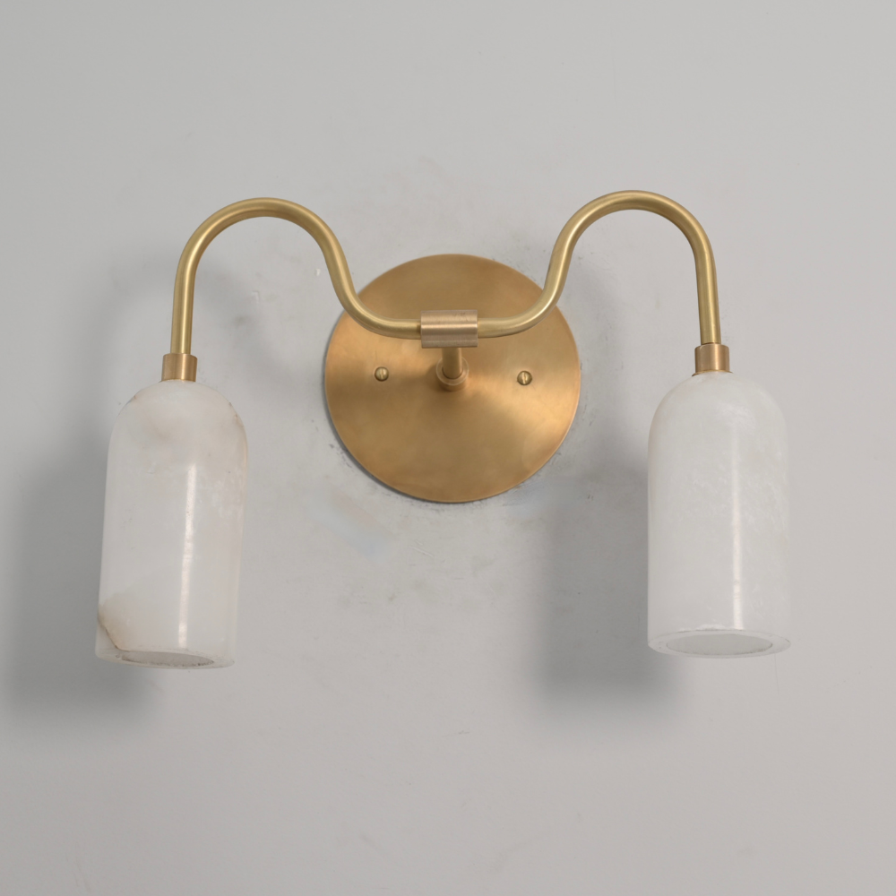 Curved brass wall lamp with two alabaster stone shades lit warm light