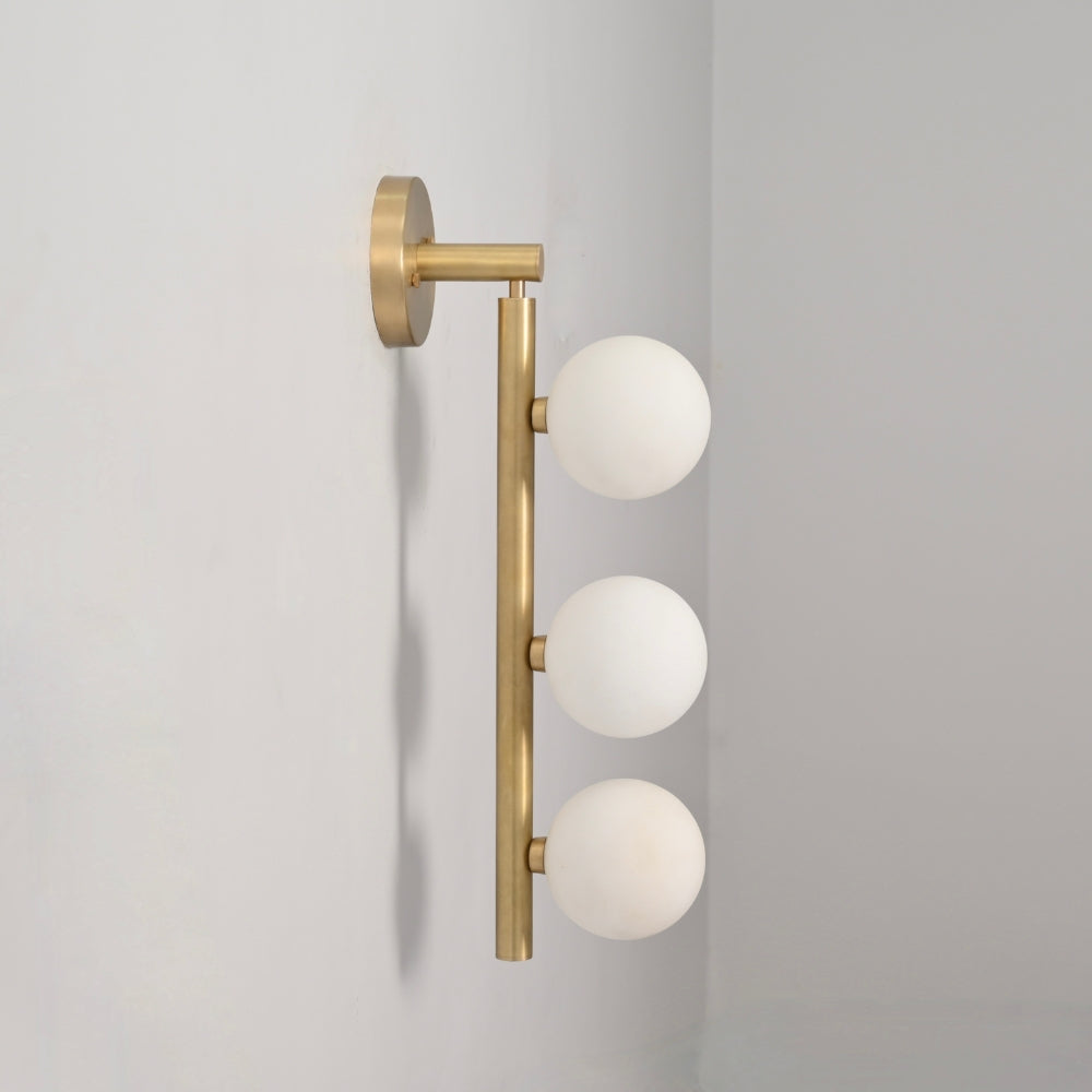 Wall-mounted light fixture with three glass globes on a gray background