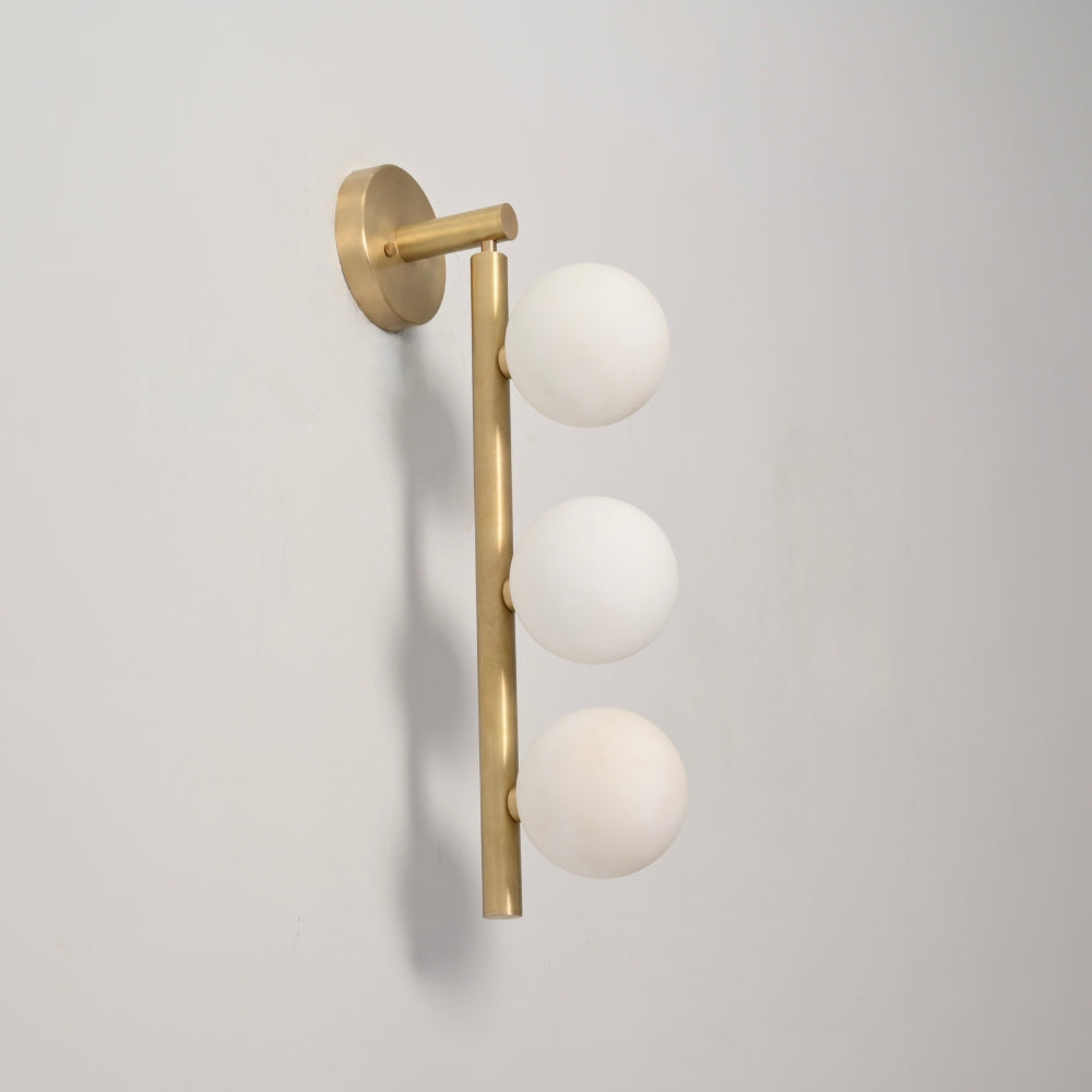 Wall-mounted light fixture with gold arm and white spherical bulbs on a gray background