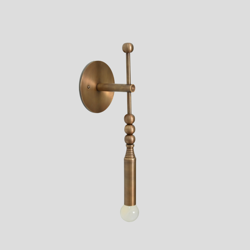 Modern Glass globe with a pure antique brass curved arm wall sconce on a gray background. 