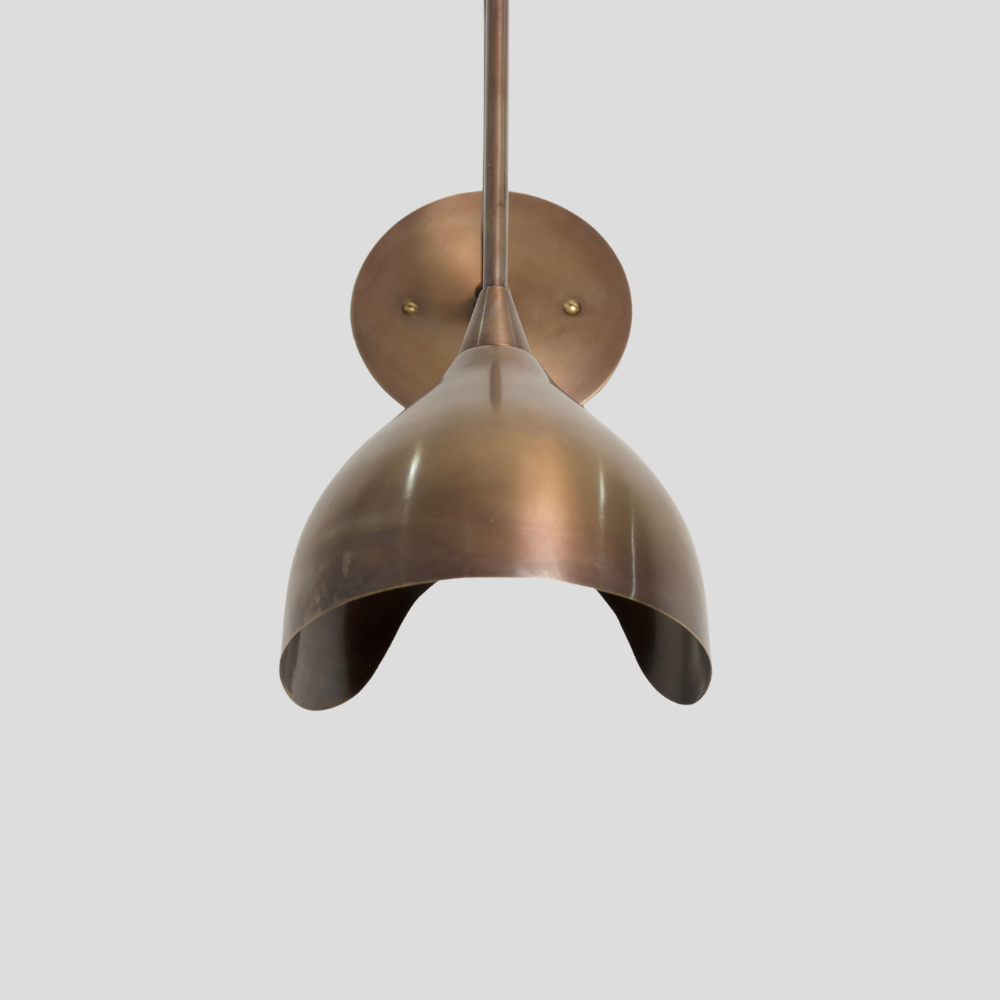 Vintage brass sconce with a sculptural curved arm wall lamp on a gray background. 