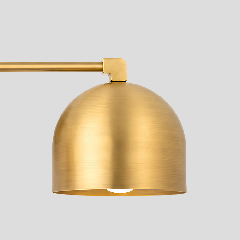 Close-up of a Double Brass Dome Vanity Light - Mid Century Linear Wall Sconce, highlighting the textured raw brass finish on the curved dome shade and horizontal connecting rod.