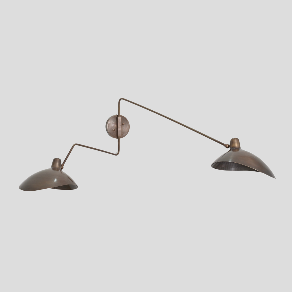 Modern double articulable brass arm wall sconce on a gray background