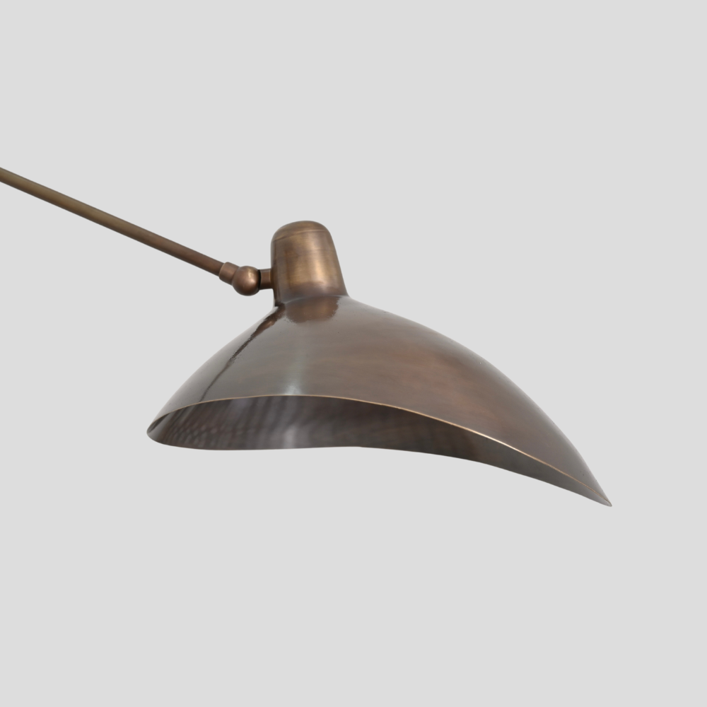 Close up on the antique brass curved shade of a mid century articulable arm wall lamp