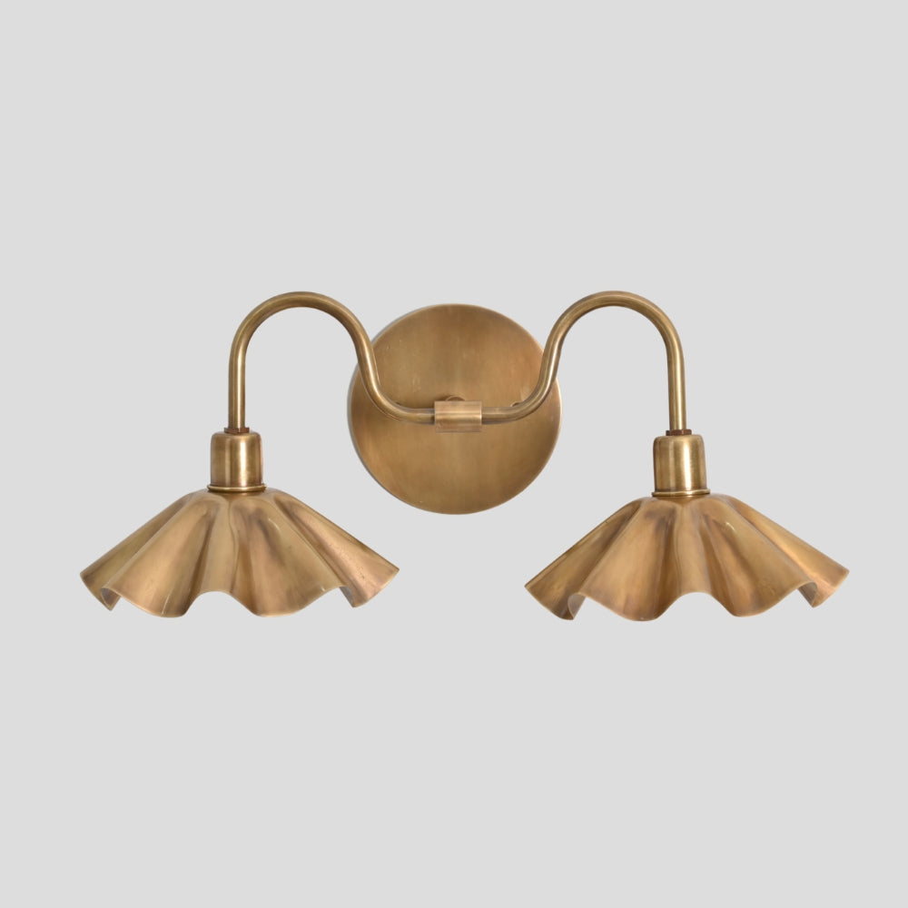 Pair of brass wall sconces with fluted lampshades on a light gray background