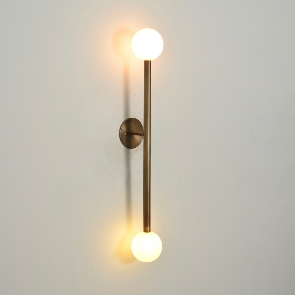 Vintage wall sconce handcrafted in a pure antique brass finish with a vertical arm and 2 frosted glass globe 