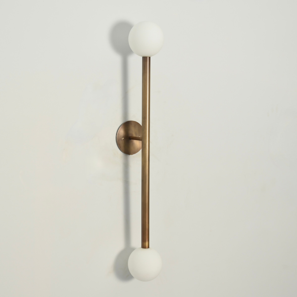 Wall-mounted light fixture with brass finish and white glass spheres on a light gray background by LightCove 