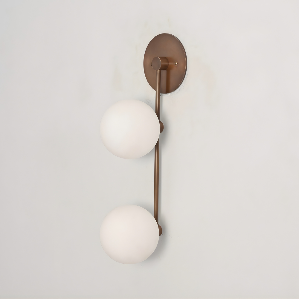 Wall light designed in a mid century design with a pure brass finish and 2 frosted glass globe 