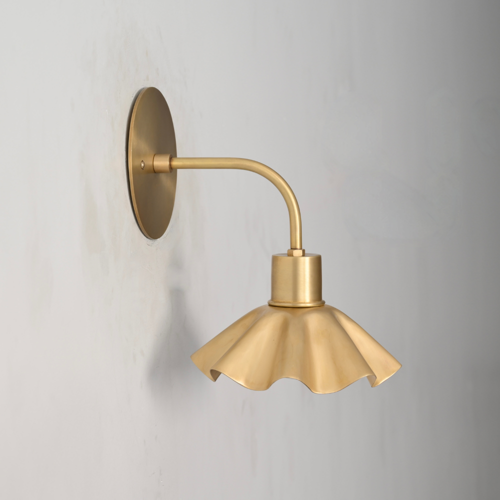 Curved Brass Flower Wall Sconce in a modern design on a gray wall 