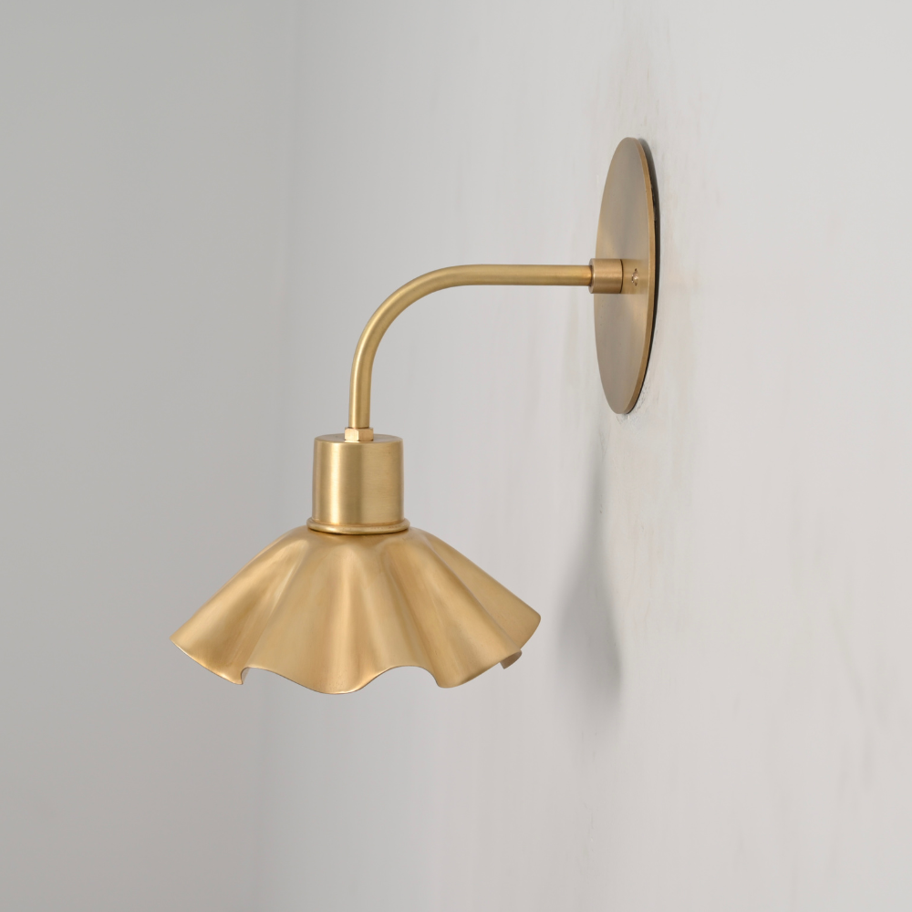 Minimalist curved brass rod petal shade wall sconce on gray wall 