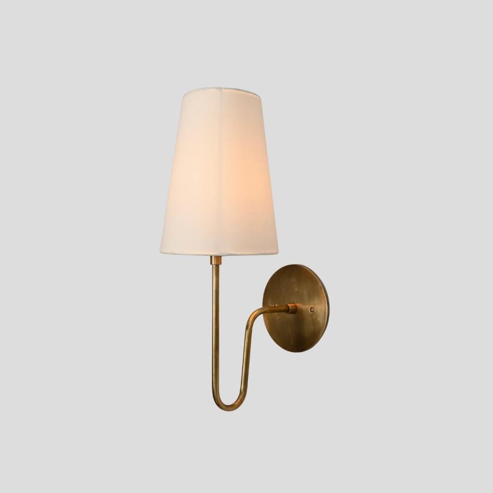 a minimalist linen shade with a brass curved rod on a gray background