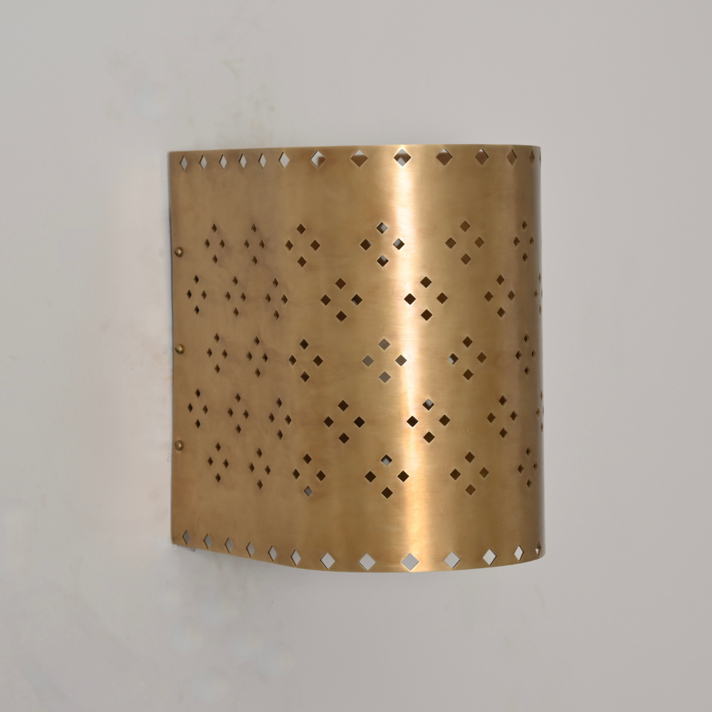 Cylindrical perforated brass wall light with soft glow