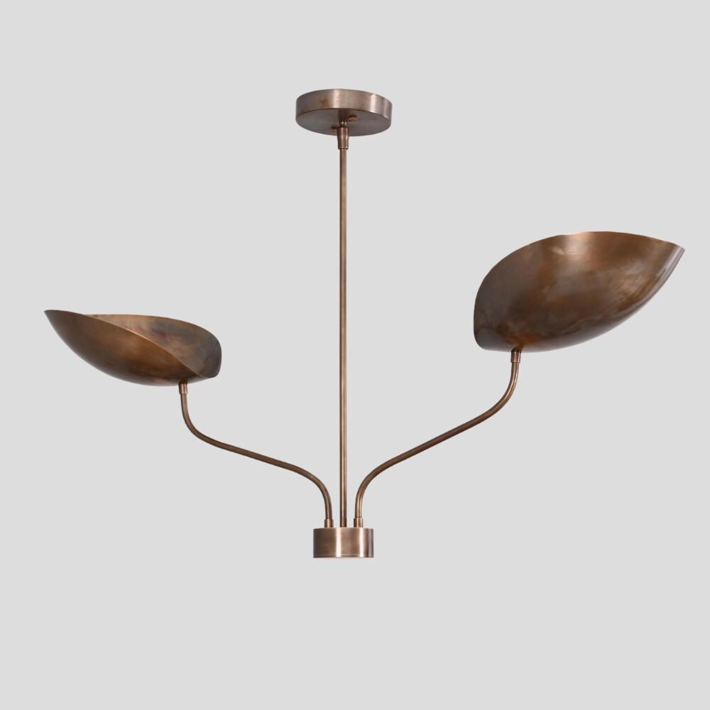 A vintage ceiling light with 2 curved arm with a antique brass finish on a gray background